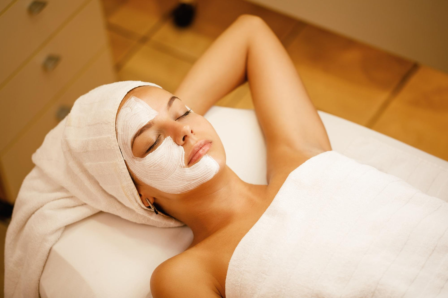 Junge Frau mit weißer Gesichtsmaske, geschlossenen Augen, entspannt, Kosmetik