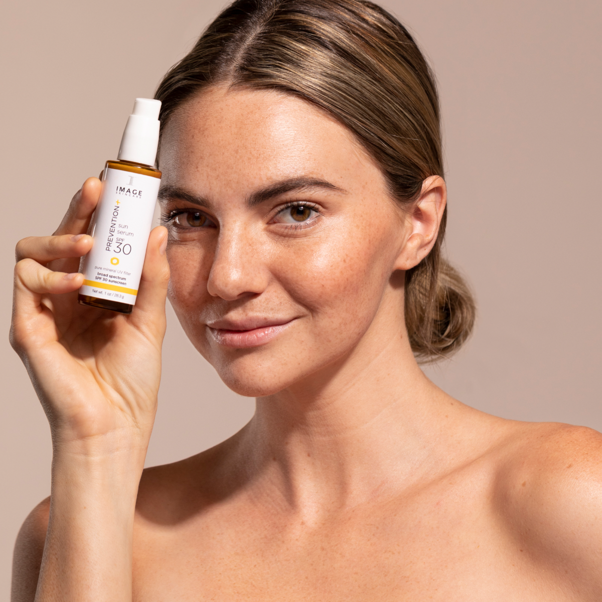 A woman showing IMAGE Skincare PREVENTION+ sun serum SPF 30