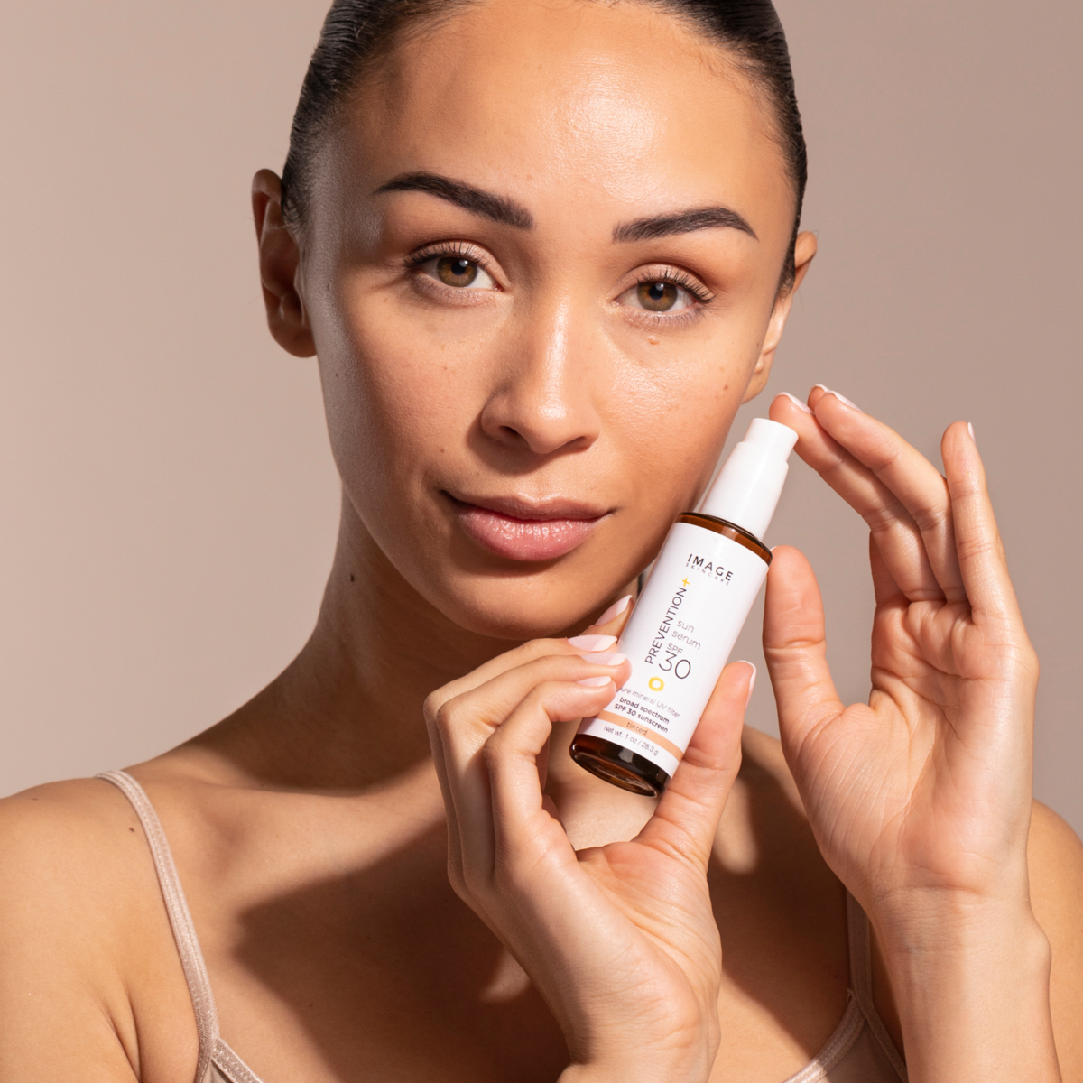 A woman showing IMAGE Skincare PREVENTION+ sun serum SPF 30 tinted