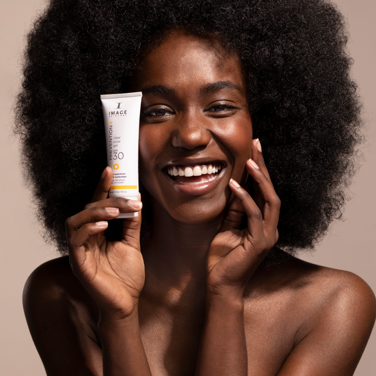 A woman showing PREVENTION+ clear solar gel SPF 30
